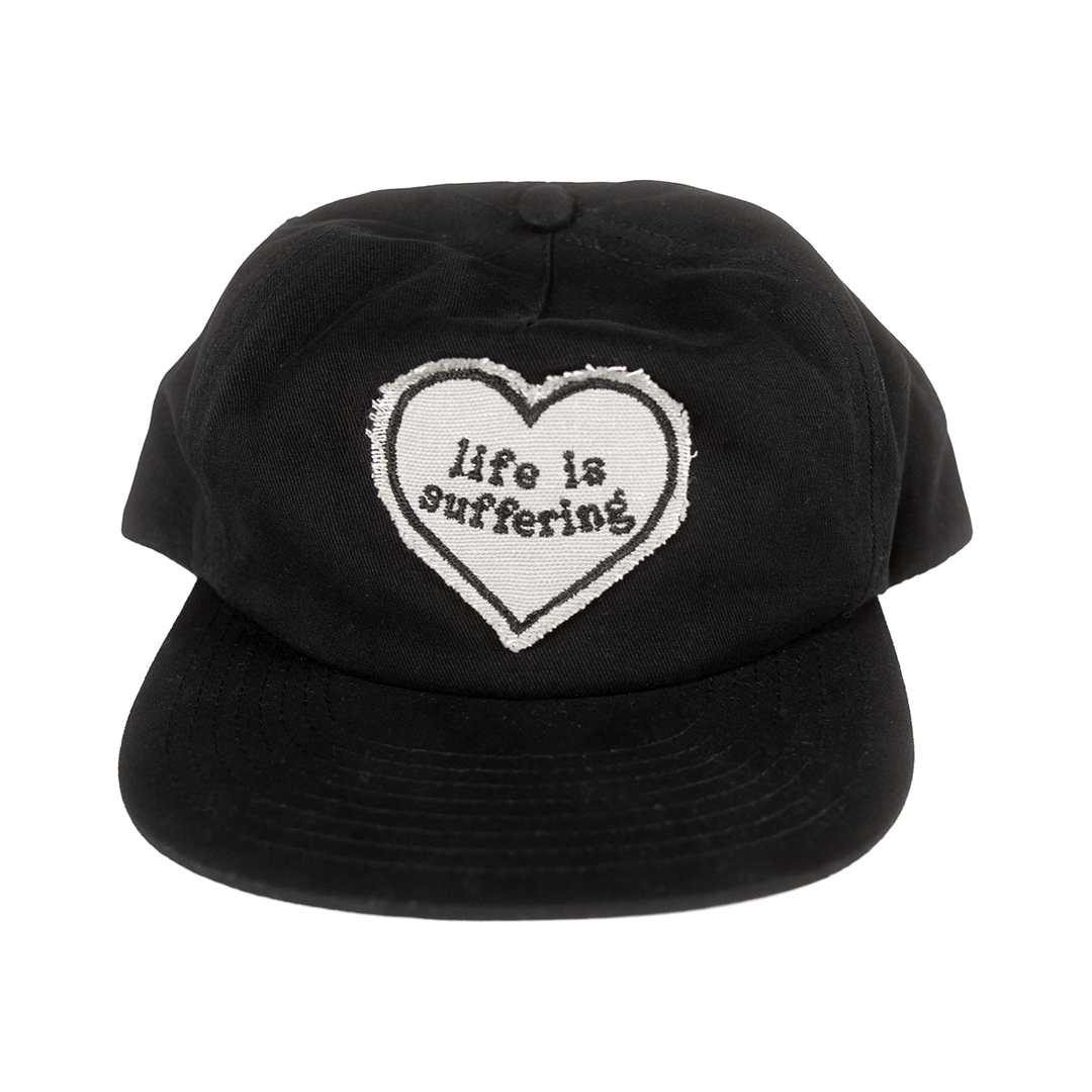 Front of black hat with a raw-edge Life Is Suffering heart patch