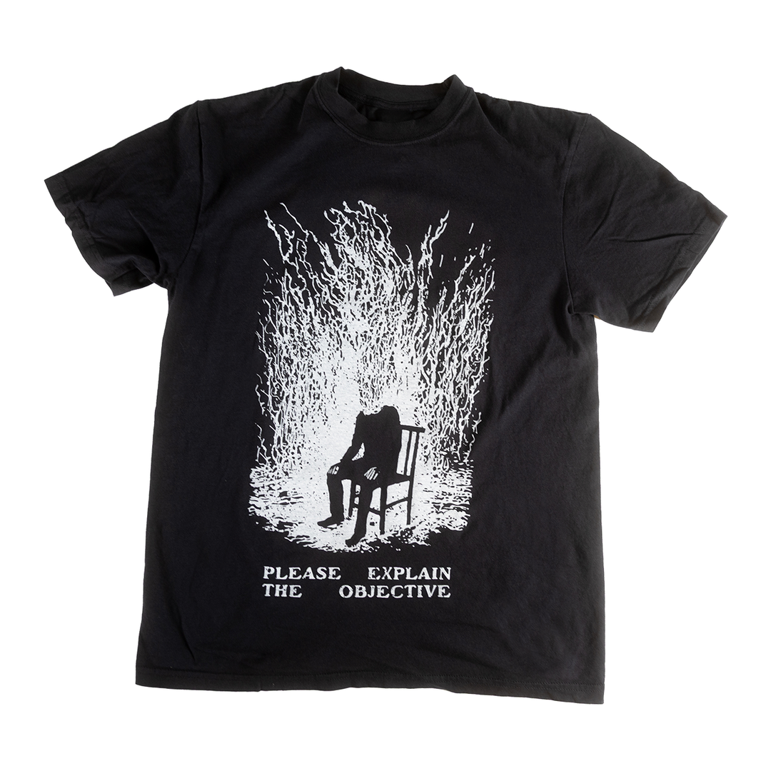 Front of black Please Explain shirt with a seated figure and Please Explain the Objective text