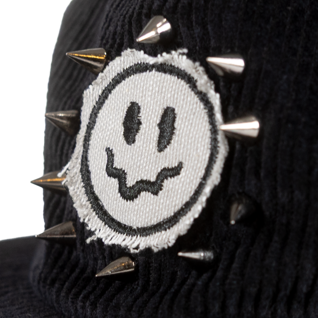 Close-up of raw-edge smiley patch and metal spikes