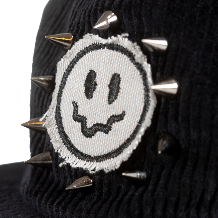 Close-up of raw-edge smiley patch and metal spikes